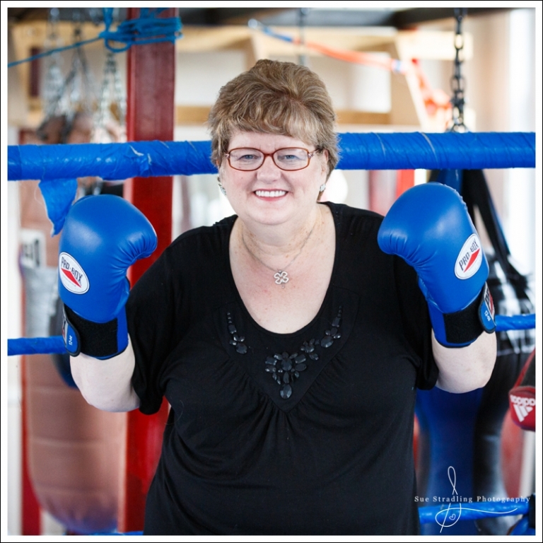 Smiling woman in boxing ring wearing boxing gloves, showing strength on International Women's Day 2019